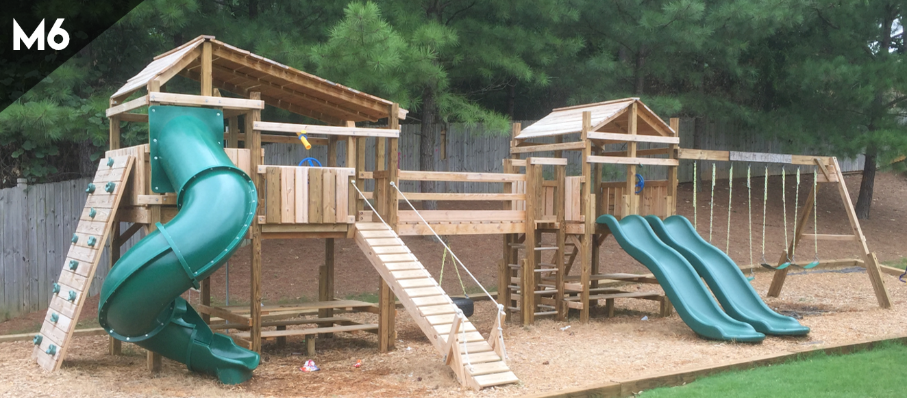 A wooden playground with a green slide and the number m6 on the bottom