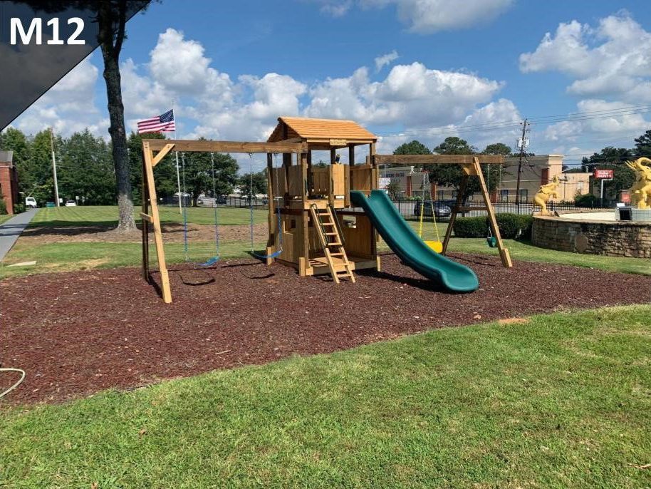 A wooden playground with a slide and swings in a park.