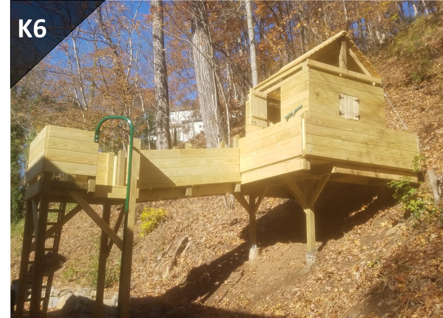 A wooden house is sitting on top of a hill surrounded by trees.