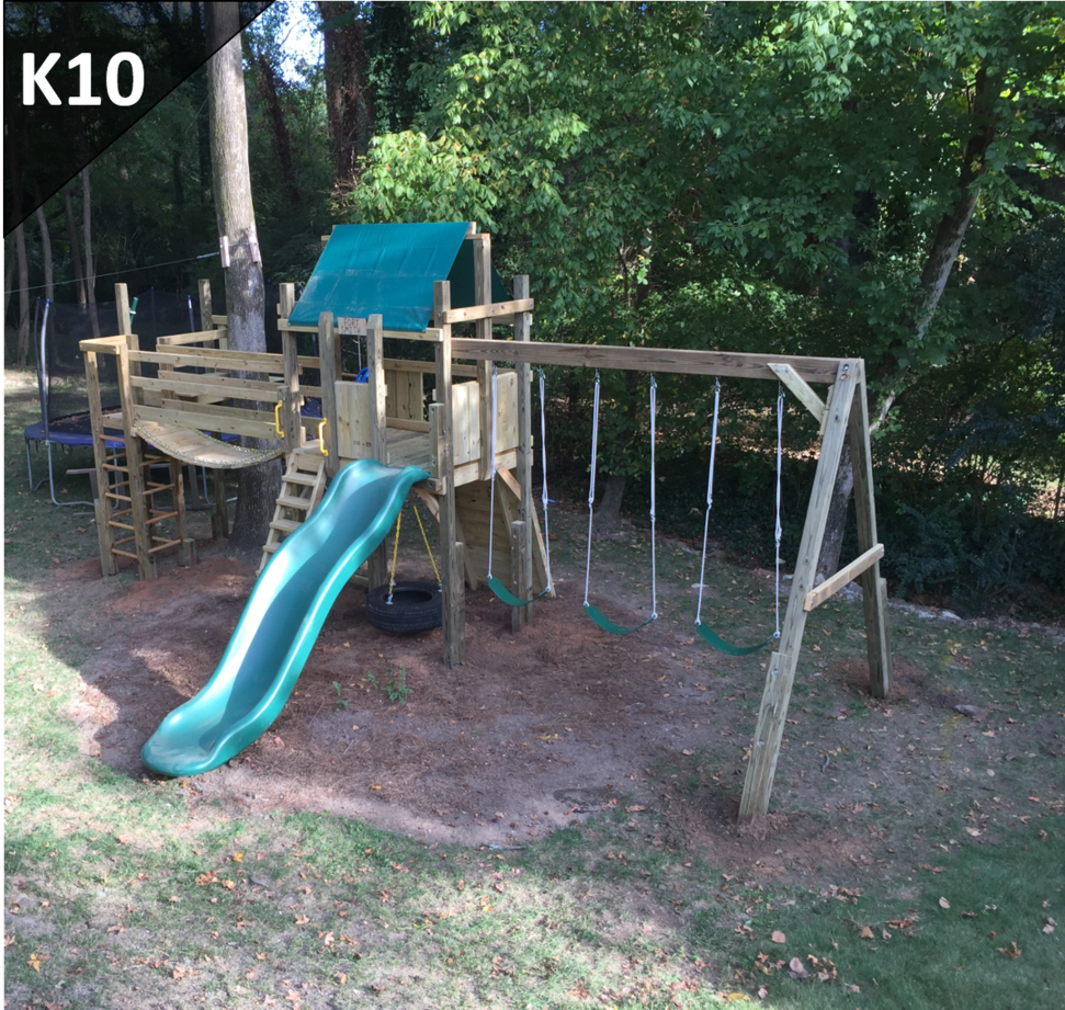 A wooden playground with a slide and swings with the number k10 on the bottom