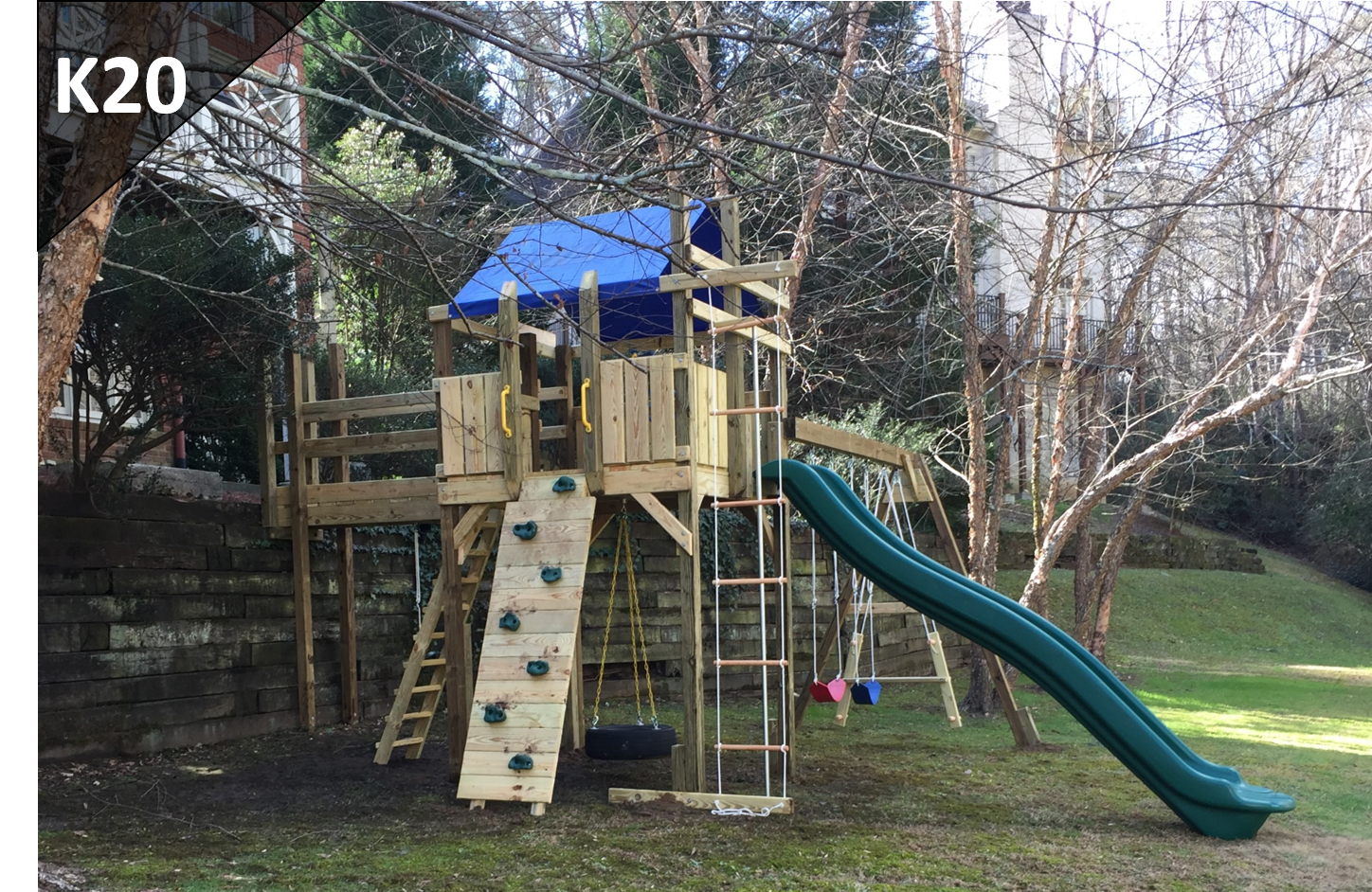 A wooden playground with a slide and stairs in a backyard.