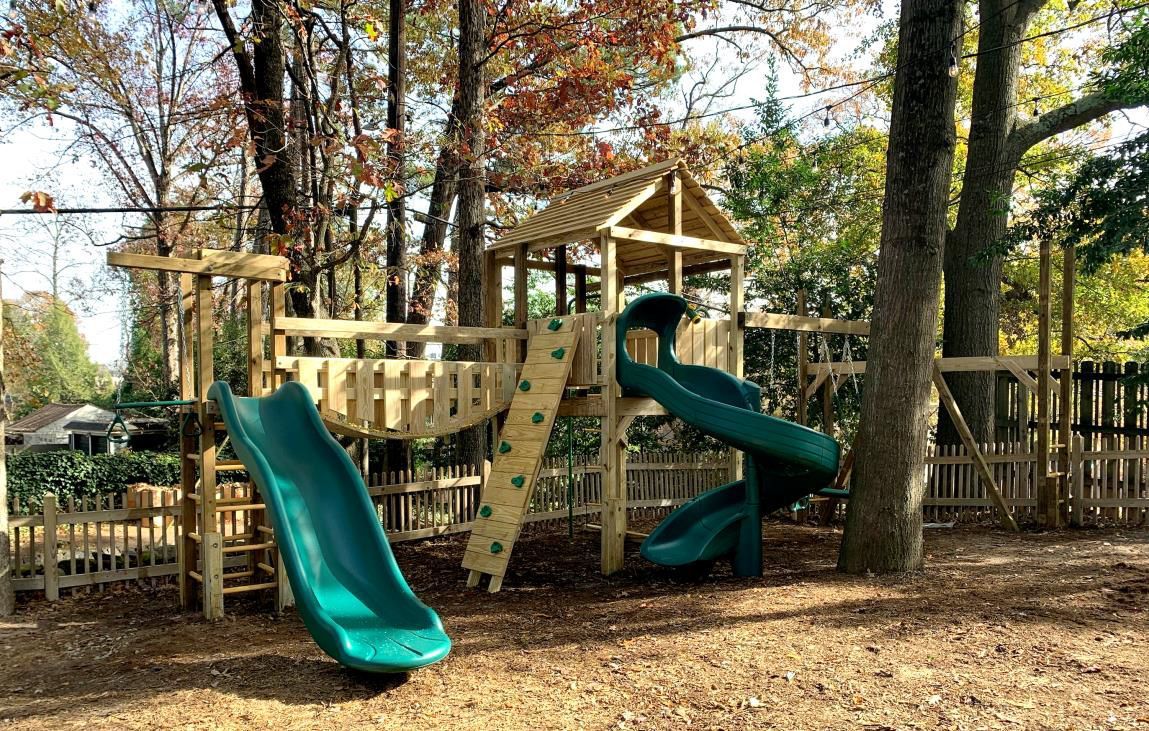 A playground with a slide and a climbing wall in a park.