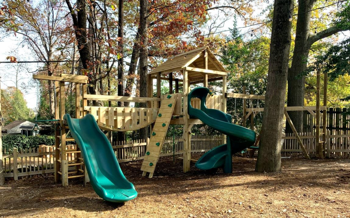 A playground with a slide and a climbing wall in a park.