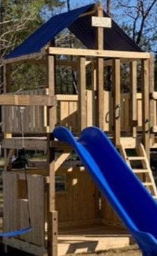 A wooden playground with a blue slide and stairs