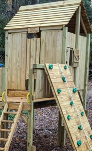 A wooden playhouse with a climbing wall and stairs.