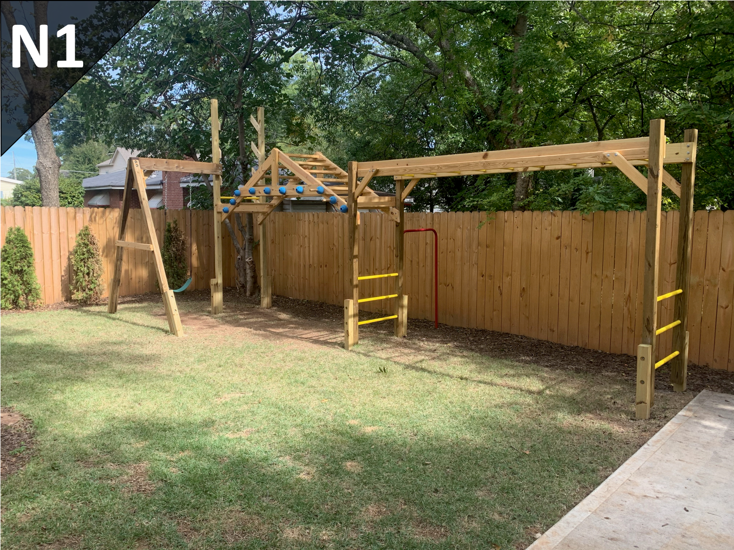 A backyard with a wooden playground and a wooden fence.
