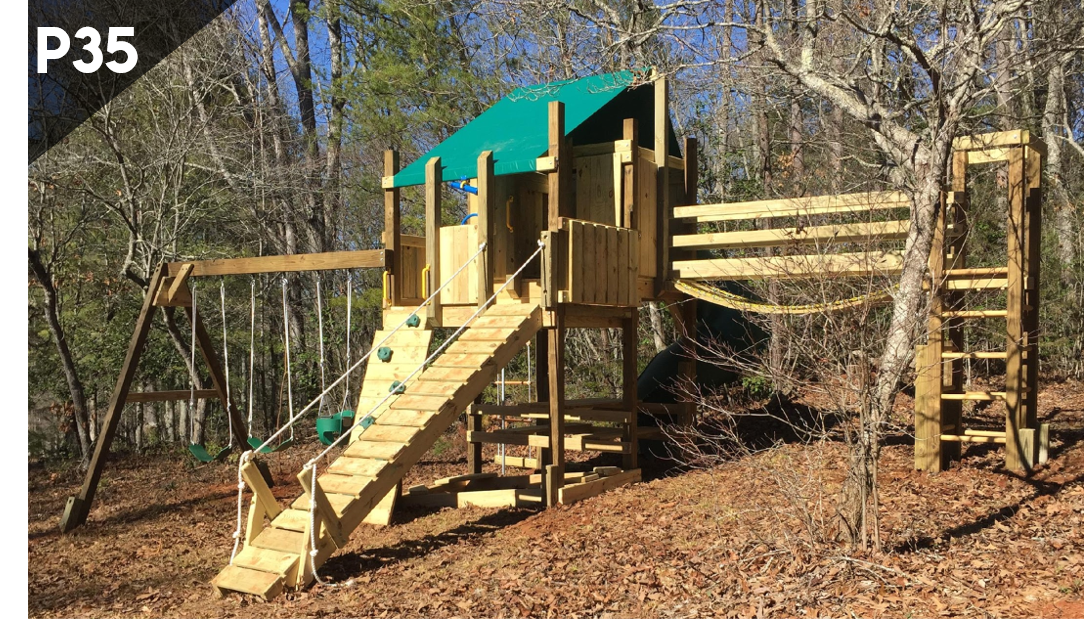 A wooden playground is sitting on top of a hill in the woods.