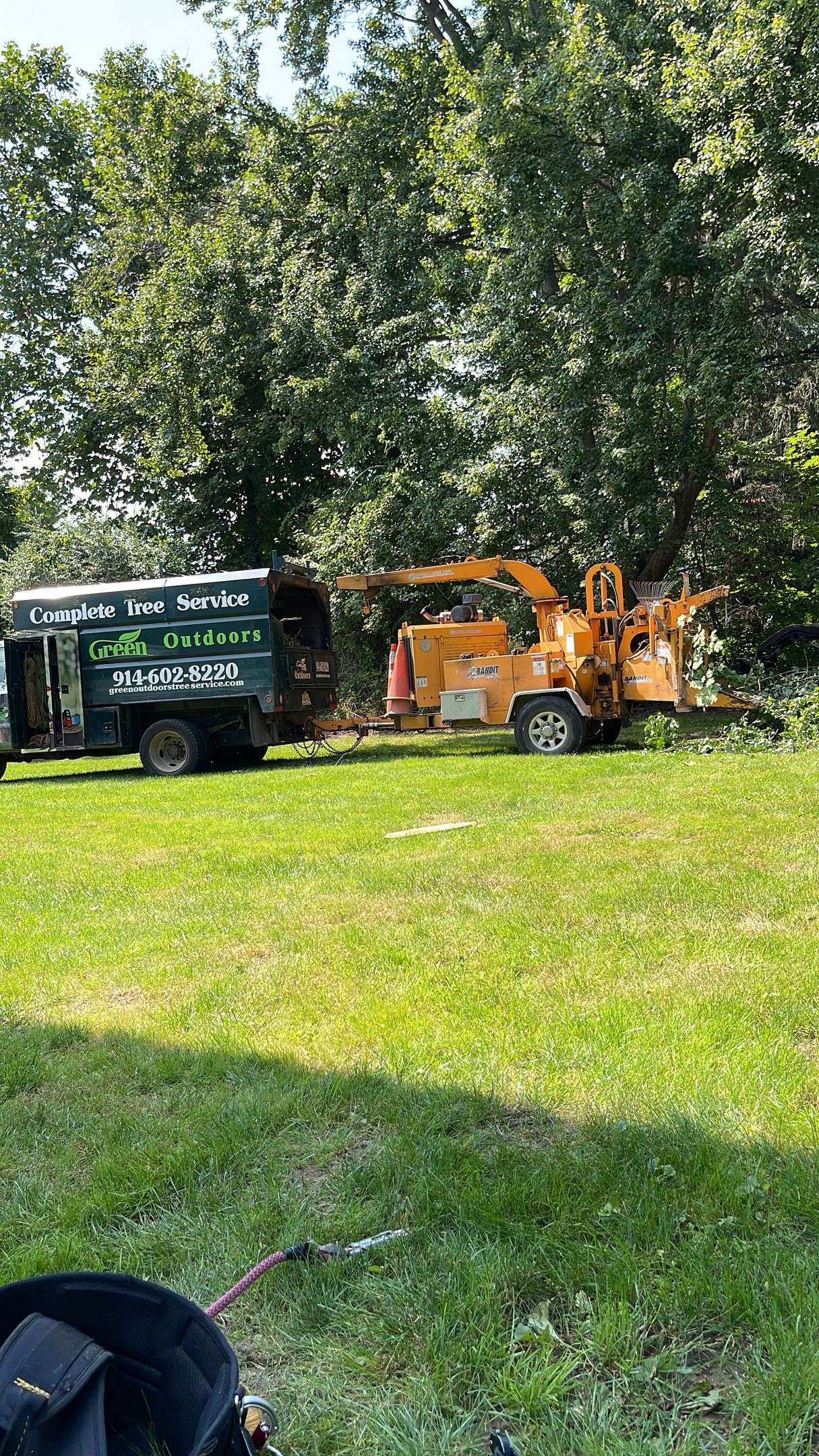 A truck is parked in a grassy field next to a tree chipper.