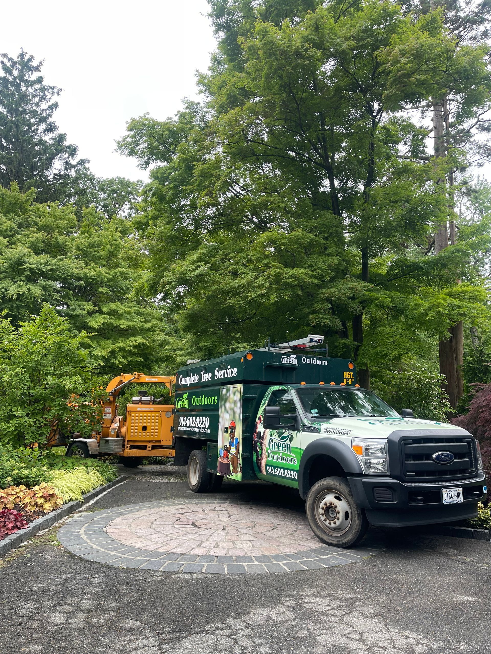 A man is driving a bulldozer next to a pile of logs.