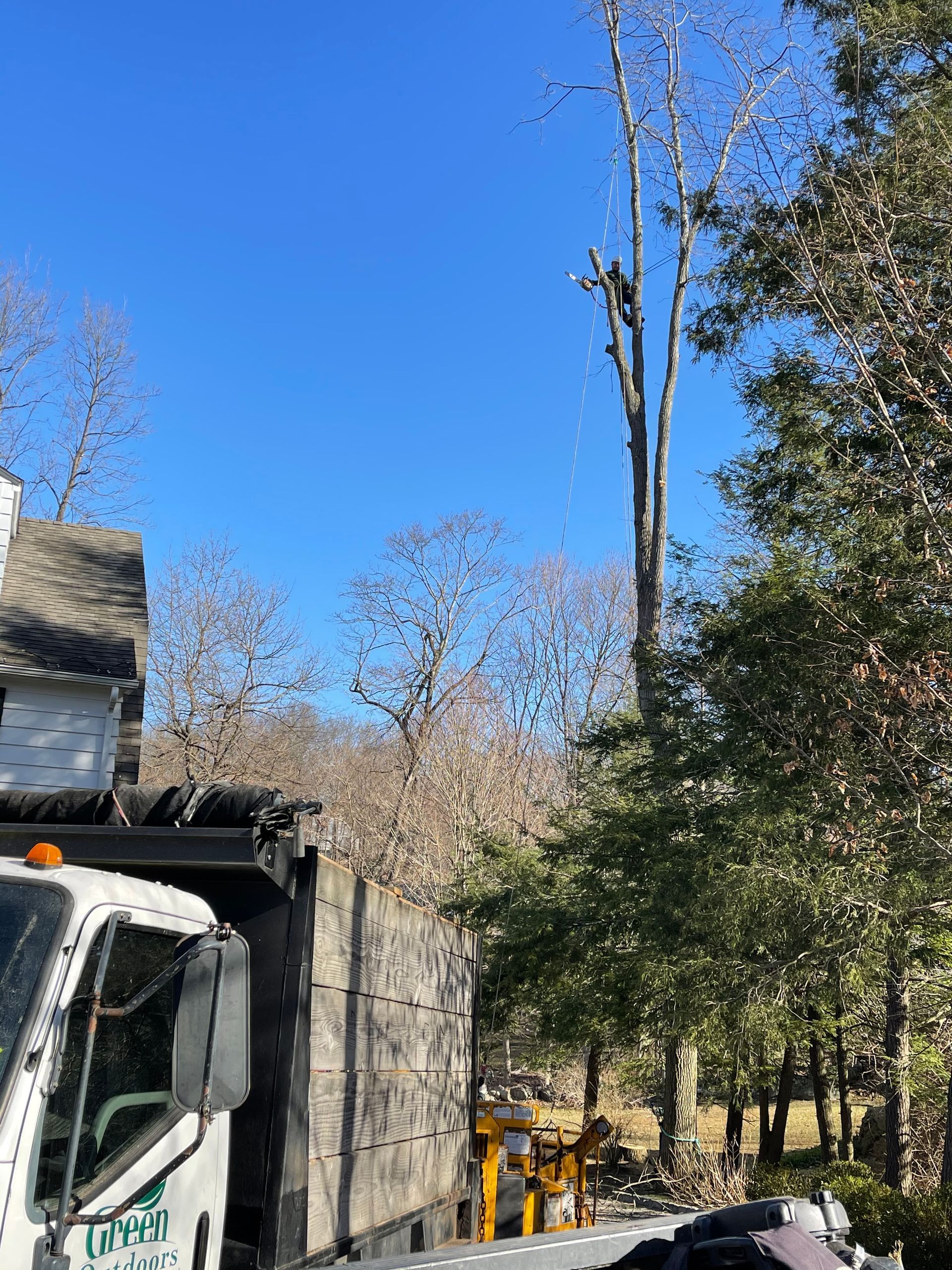 A white truck is parked in front of a house with a tree in the background.