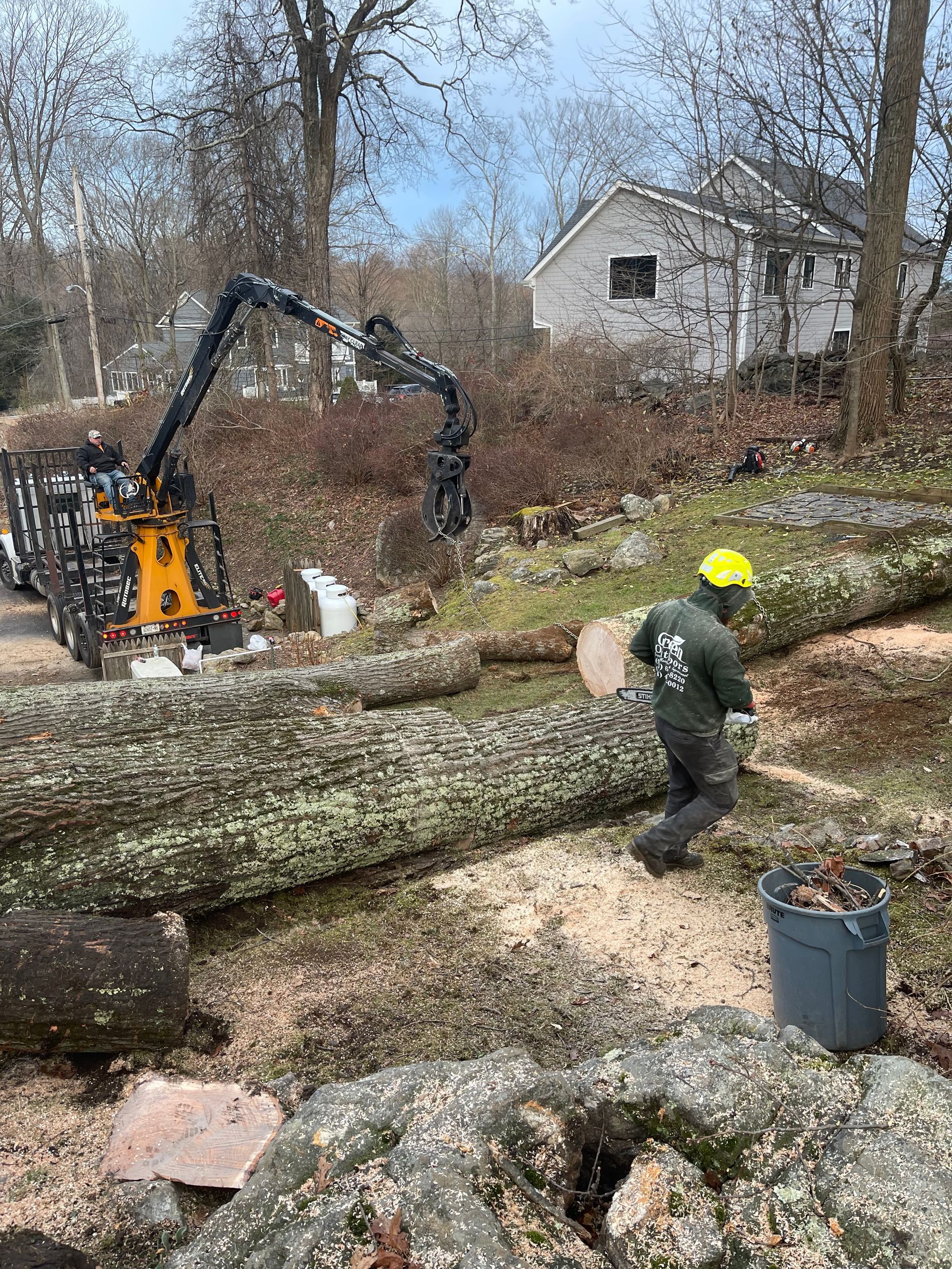 A man is standing next to a large log in a yard.