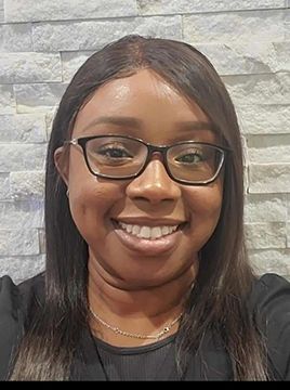 A woman wearing glasses and a black shirt is smiling for the camera.