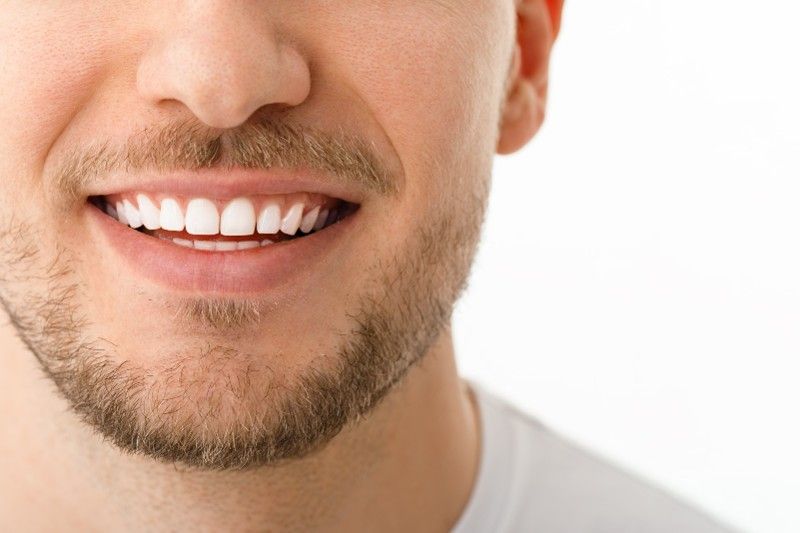 A close up of a man 's mouth with a beard and white teeth.