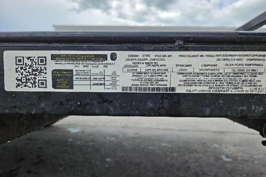 Close-up of a vehicle identification label with QR code on a black metal trailer hitch.