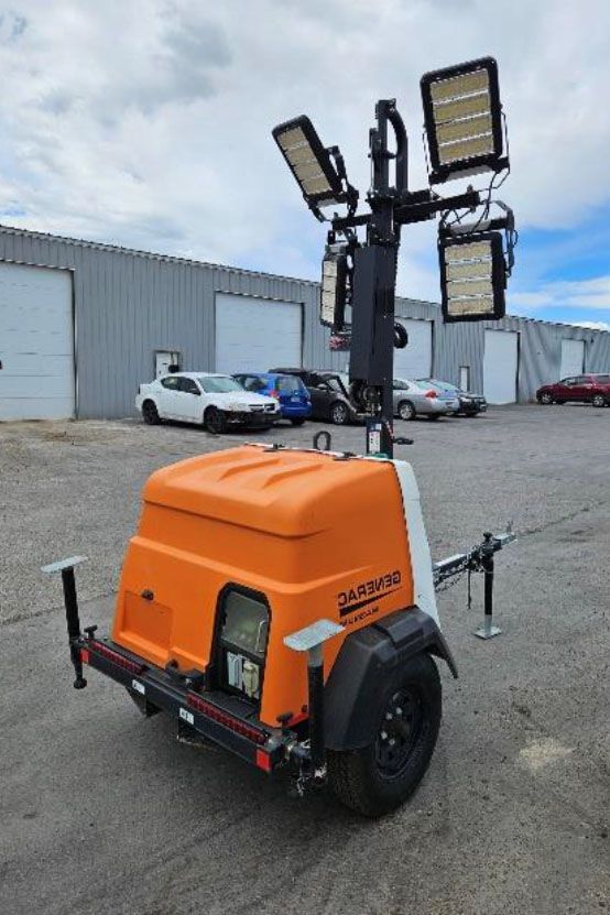 Orange portable light tower trailer with four LED panels in an industrial lot