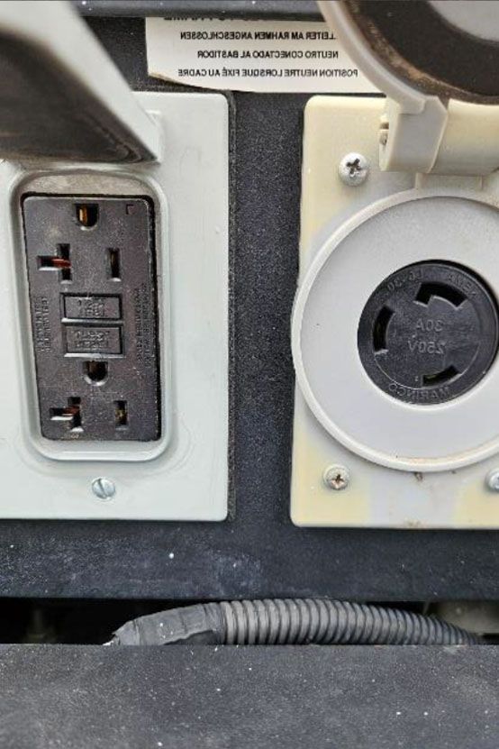 Close-up of an electrical outlet and round power socket on a gray panel