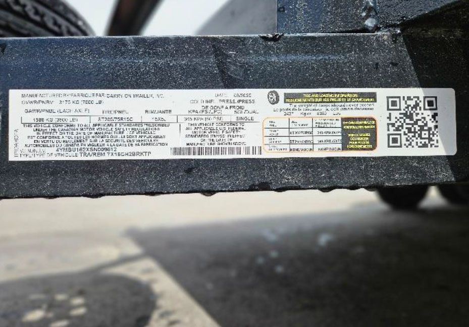 Close-up of a trailer frame label and QR code on a black metal beam.