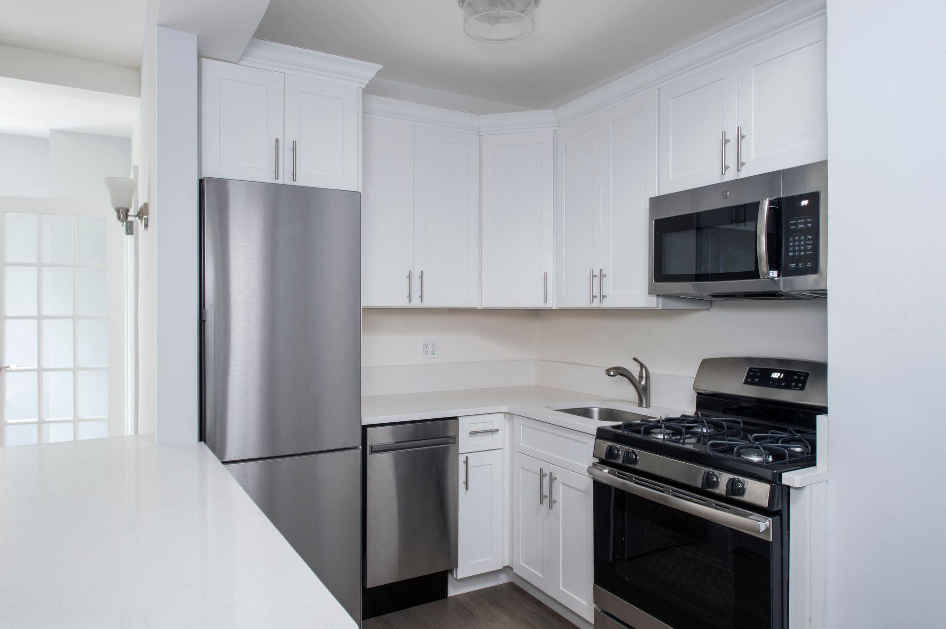 Bright white kitchen with stainless steel appliances and dark countertops