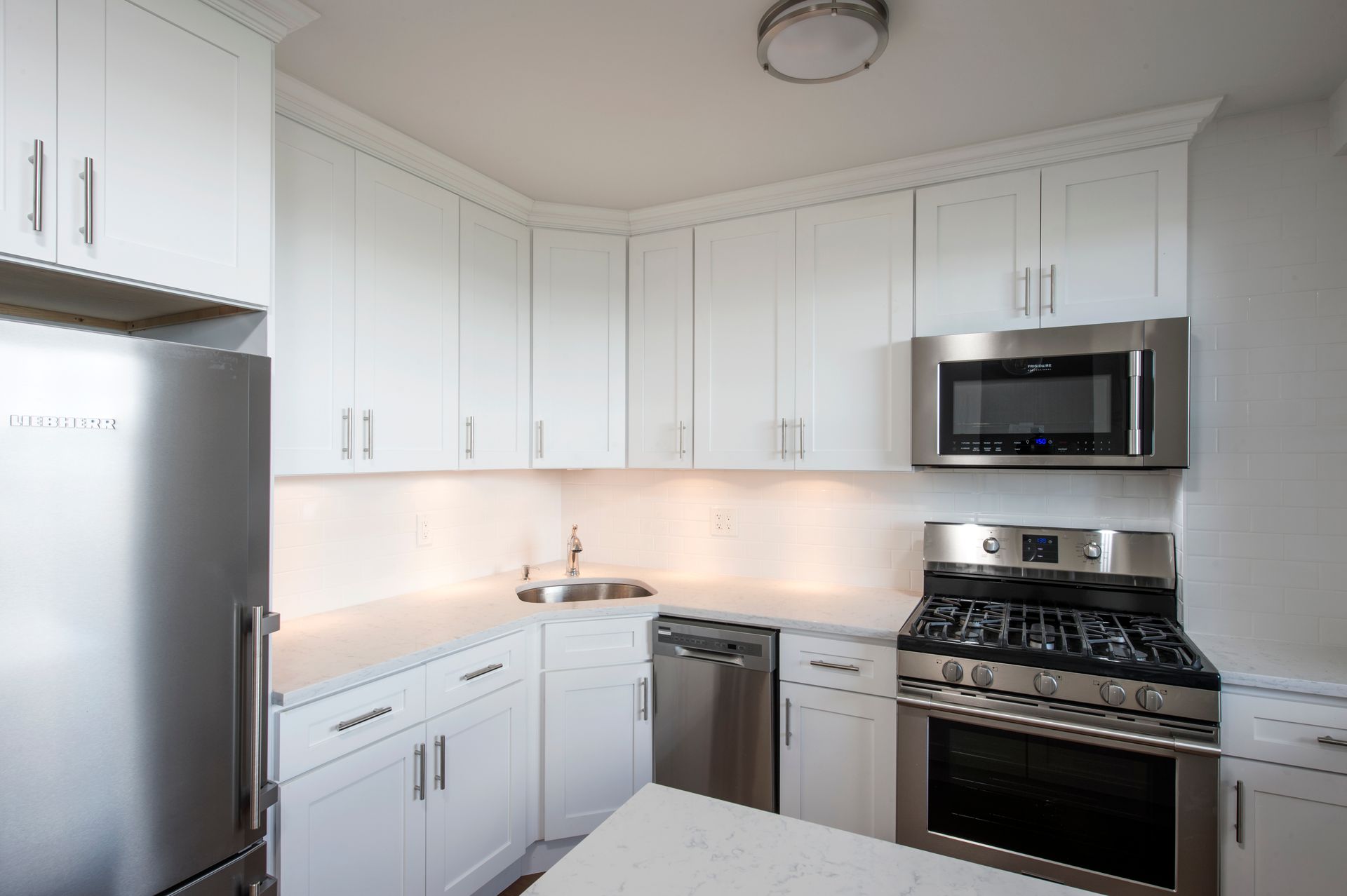 Bright white modern kitchen with stainless steel appliances and under-cabinet lighting