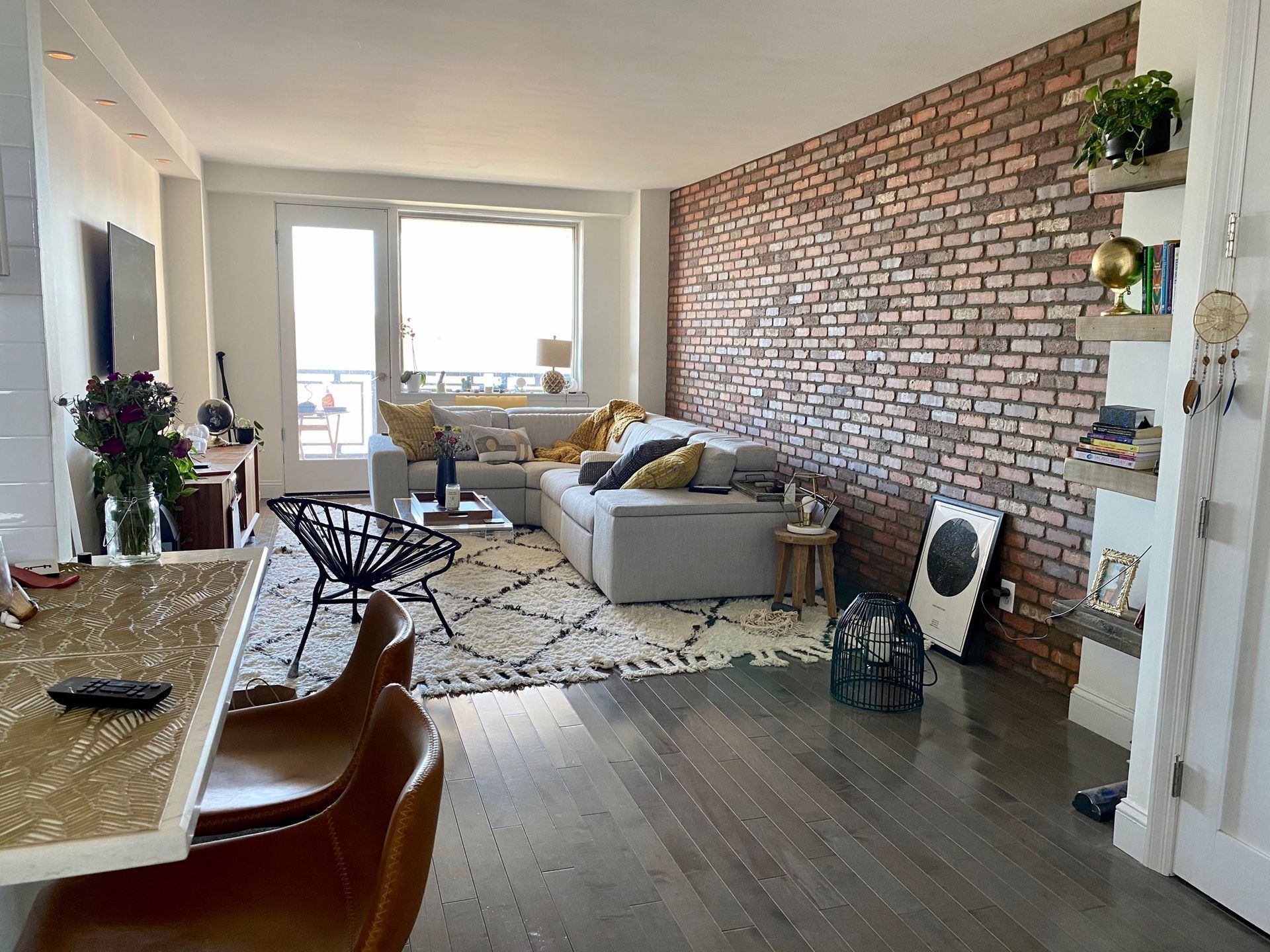 Bright living room with brick accent wall, sofa, rug, and large window light