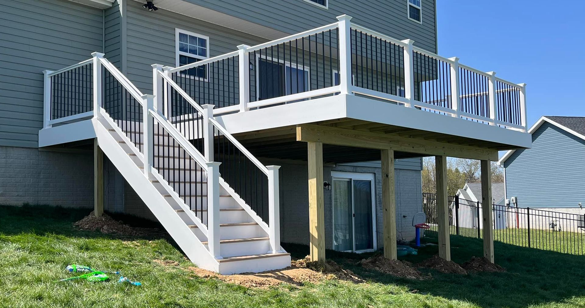 A deck with stairs leading up to it and a house in the background.