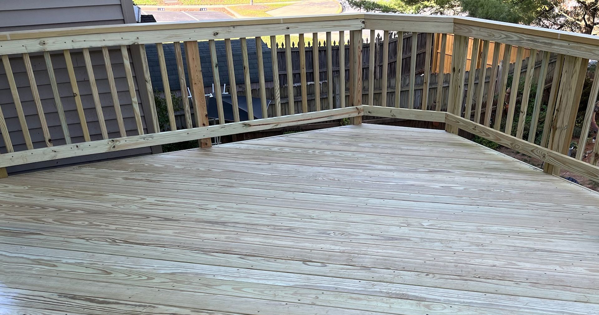 An empty deck with a wooden railing and a fence.