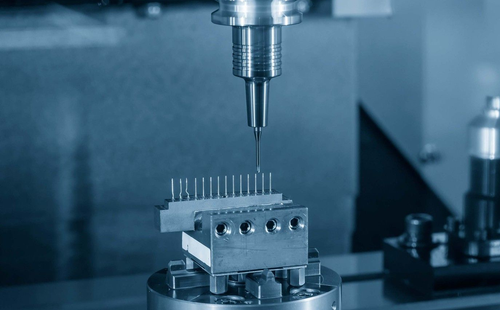 CNC machine precision-drilling a metal block in a blue-lit workshop