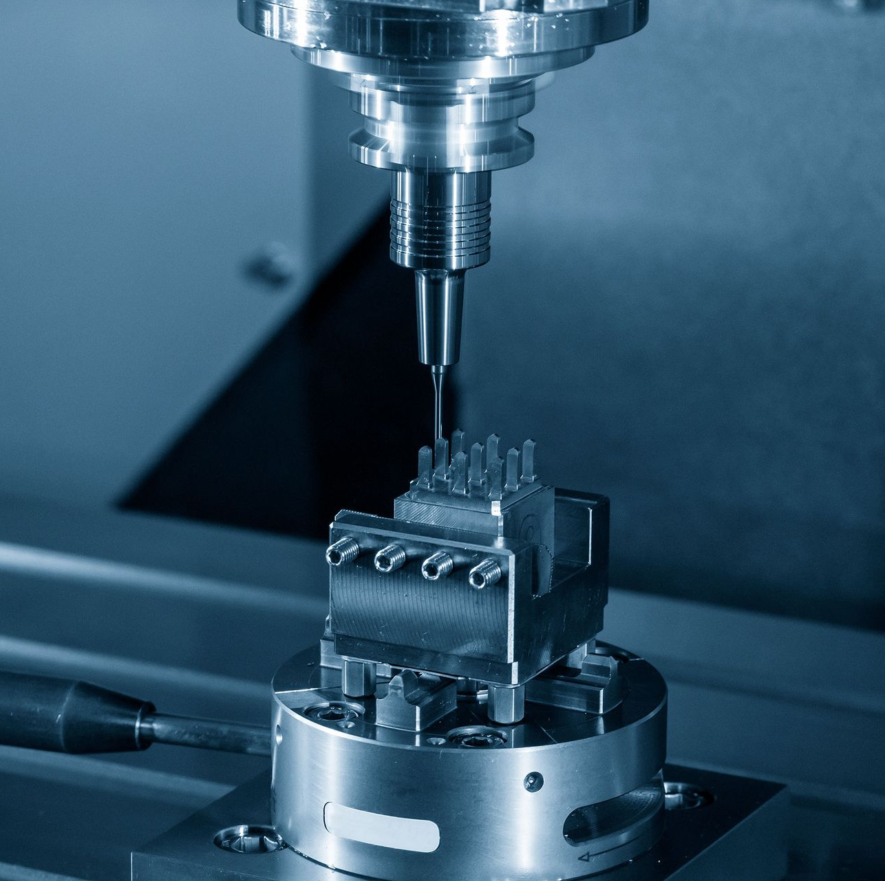 CNC milling machine precision-cutting a metal part in a blue-toned workshop