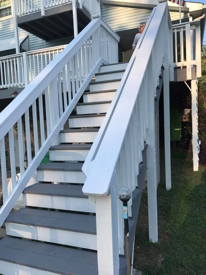 A set of stairs leading up to a house with a white railing