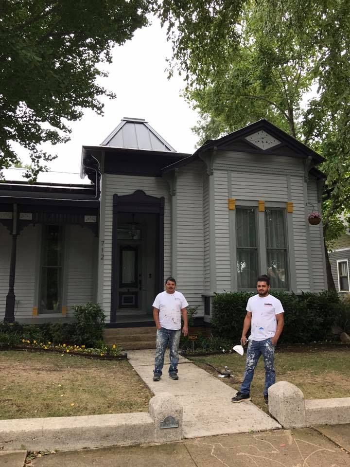 Two men are standing in front of a white house.