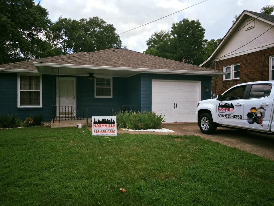 A white truck is parked in front of a blue house
