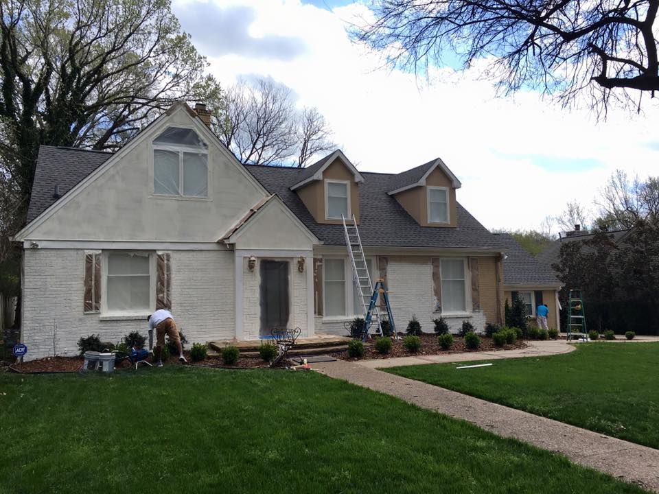 A man is painting the outside of a house