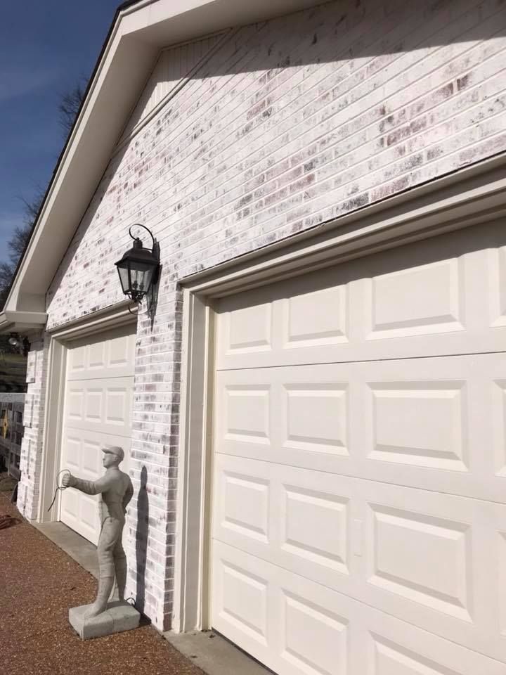 There is a statue of a man standing next to a garage door.