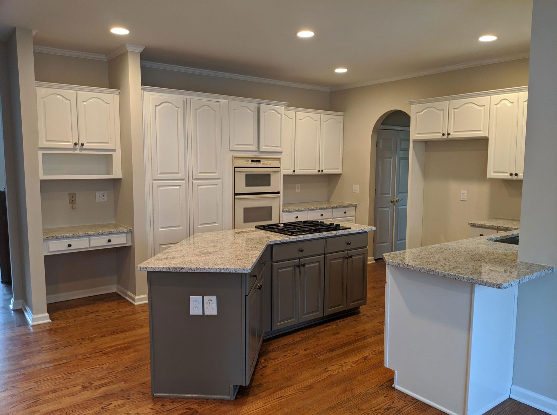 A kitchen with white cabinets , granite counter tops , and a large island.
