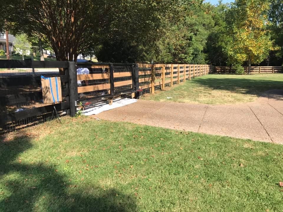A wooden fence surrounds a lush green field.