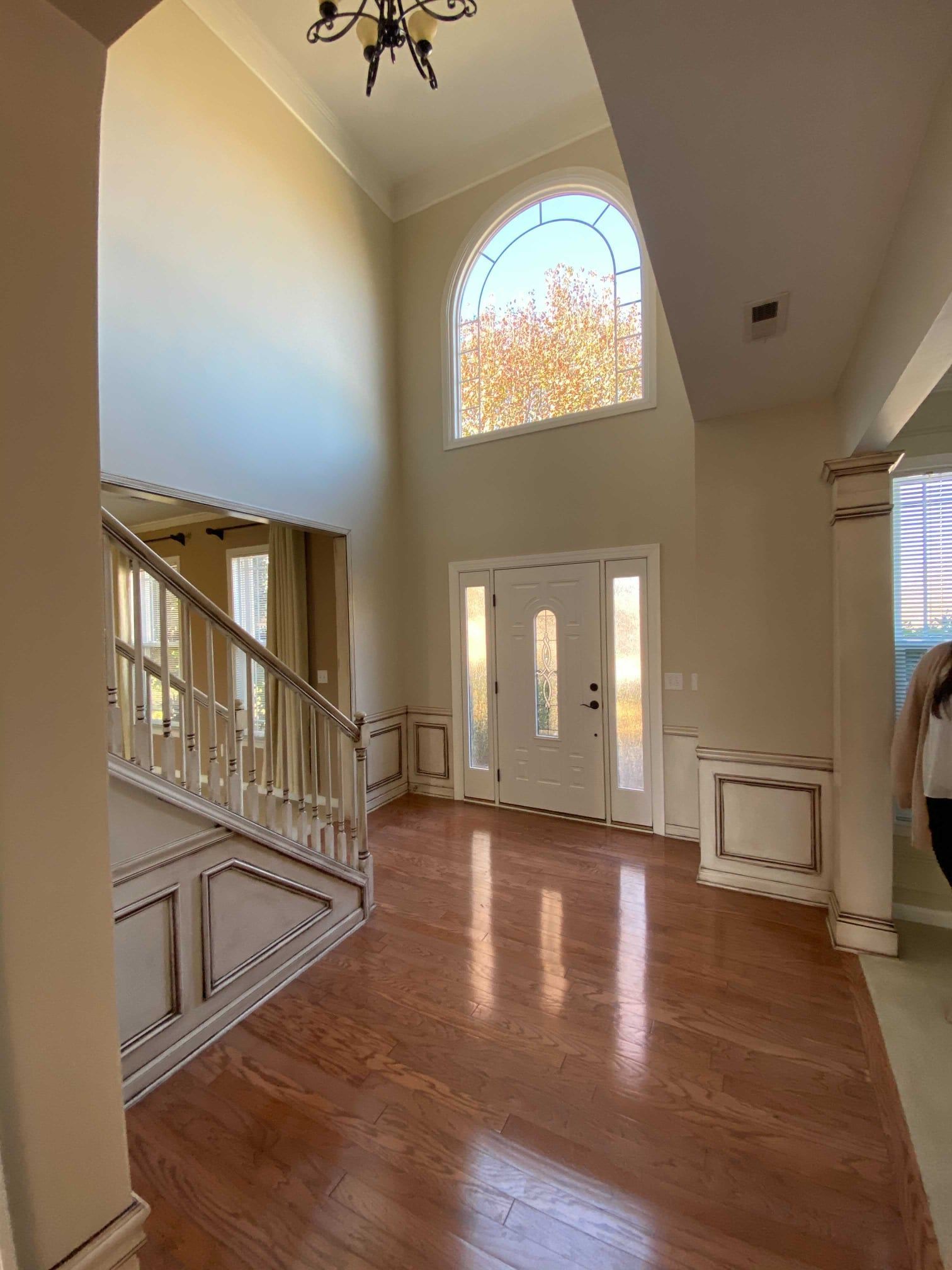 An empty hallway with a staircase and a large window.