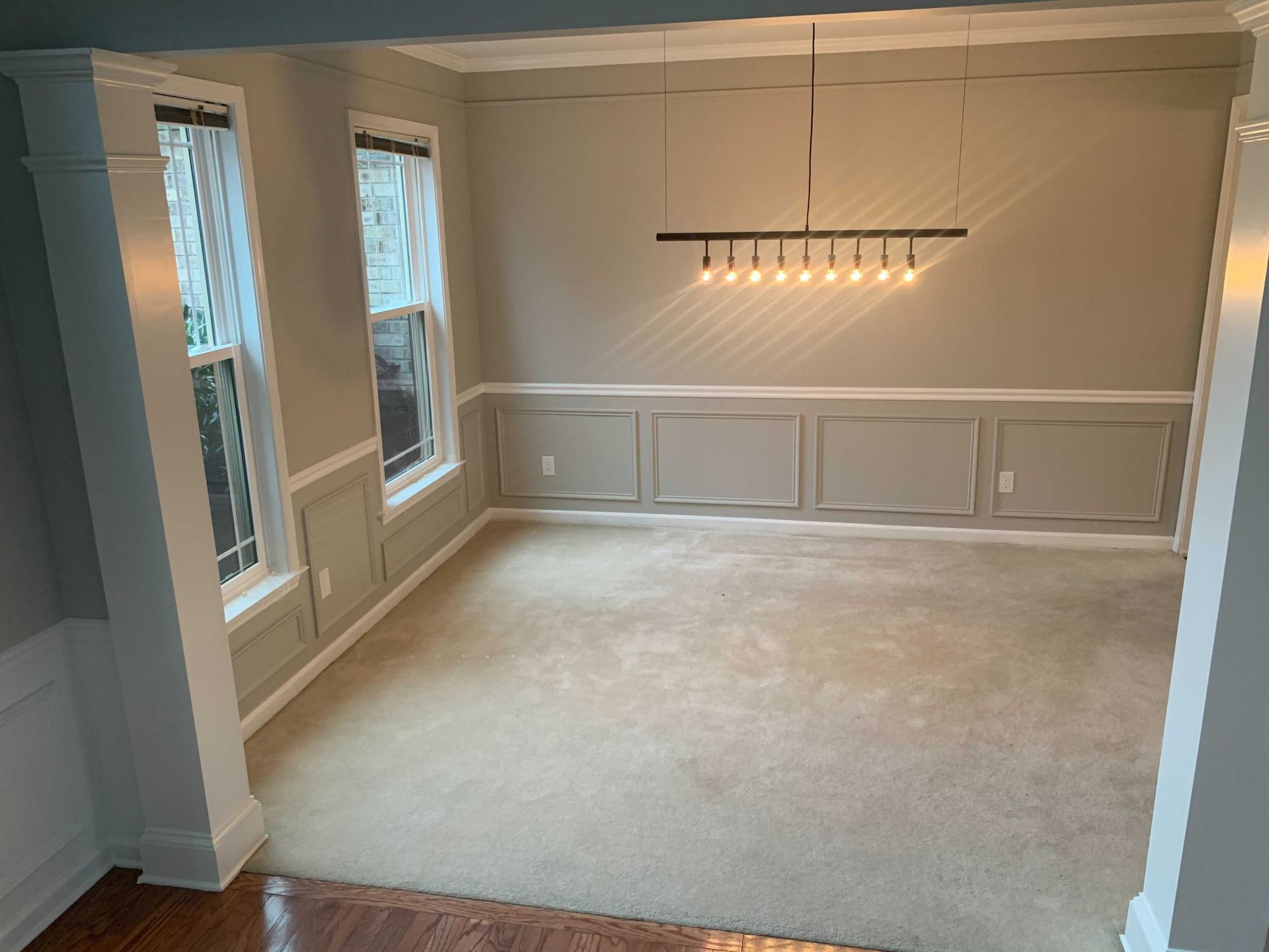 An empty dining room with a chandelier hanging from the ceiling.