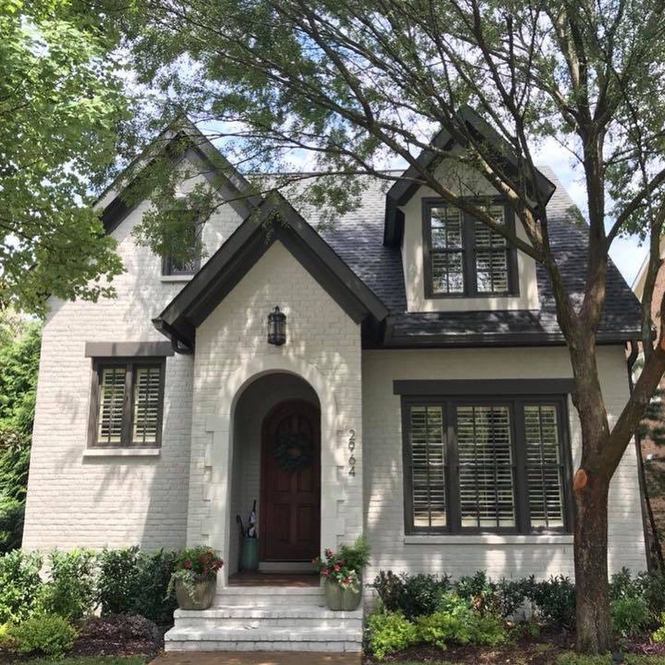 A white brick house with a black roof