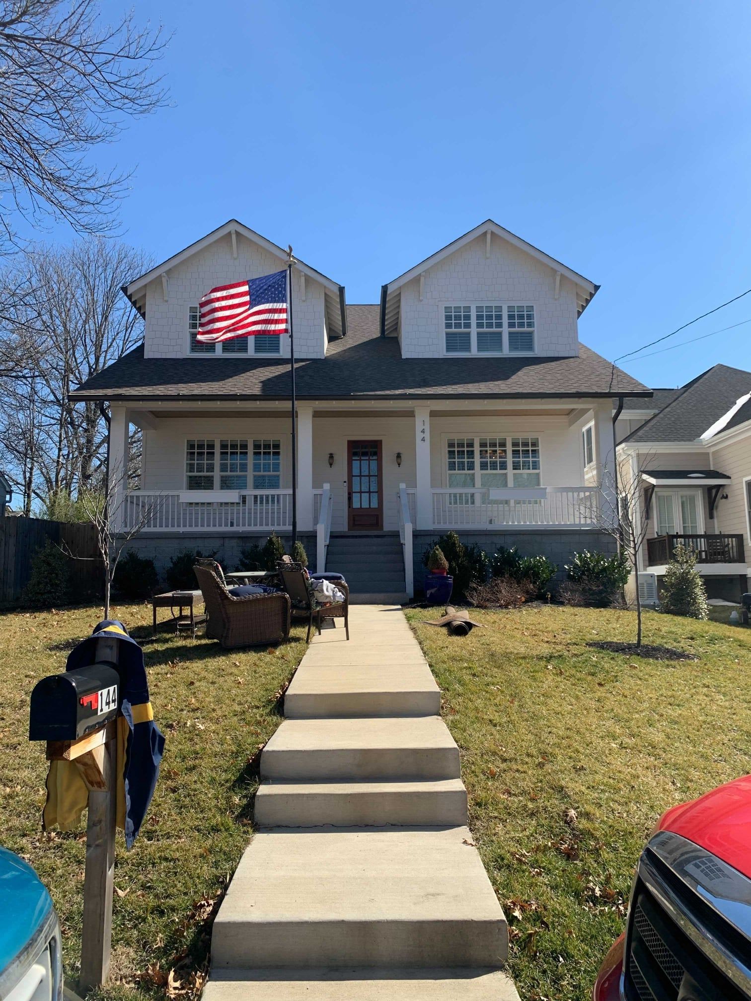 A large white house with a red truck parked in front of it.