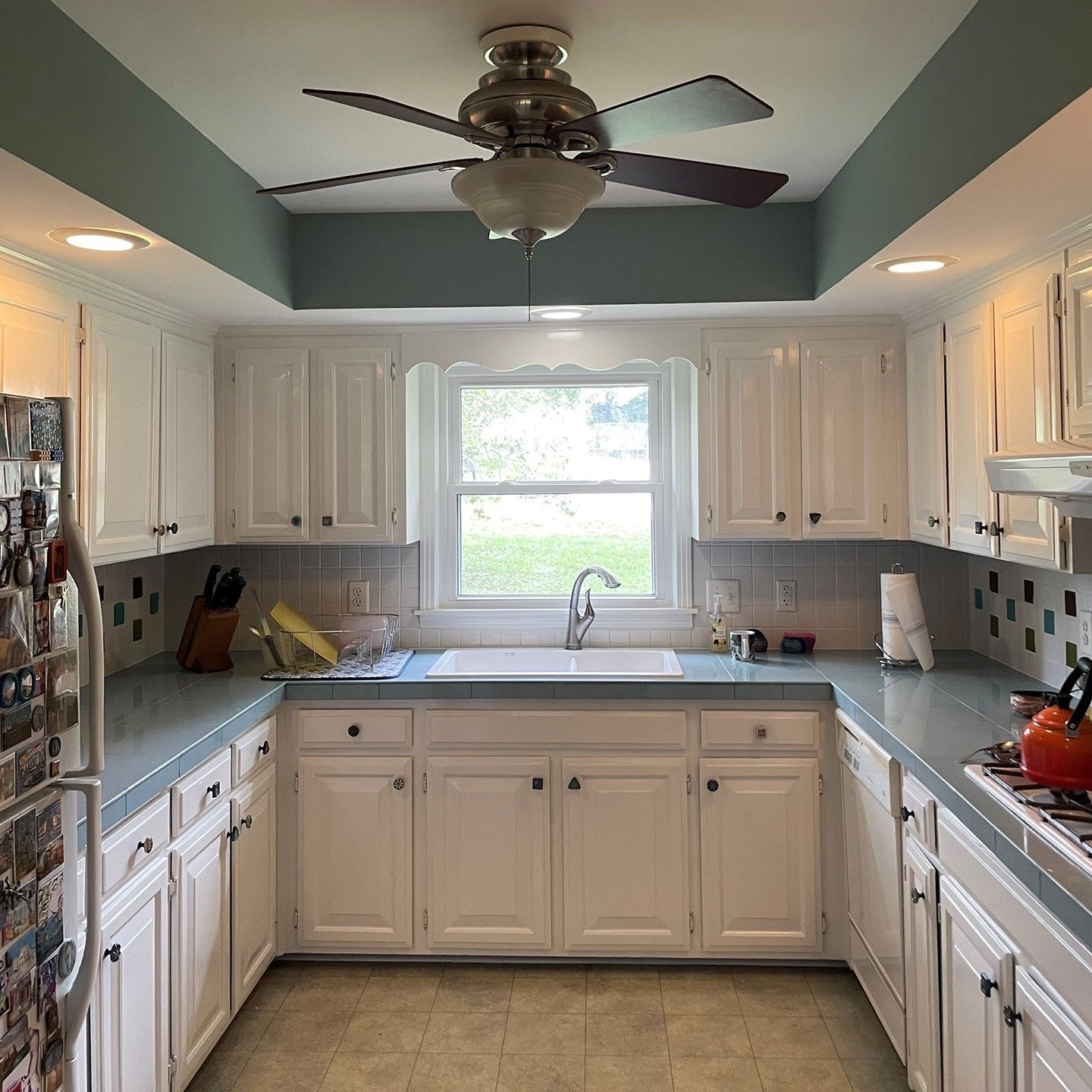 A kitchen with white cabinets and a ceiling fan