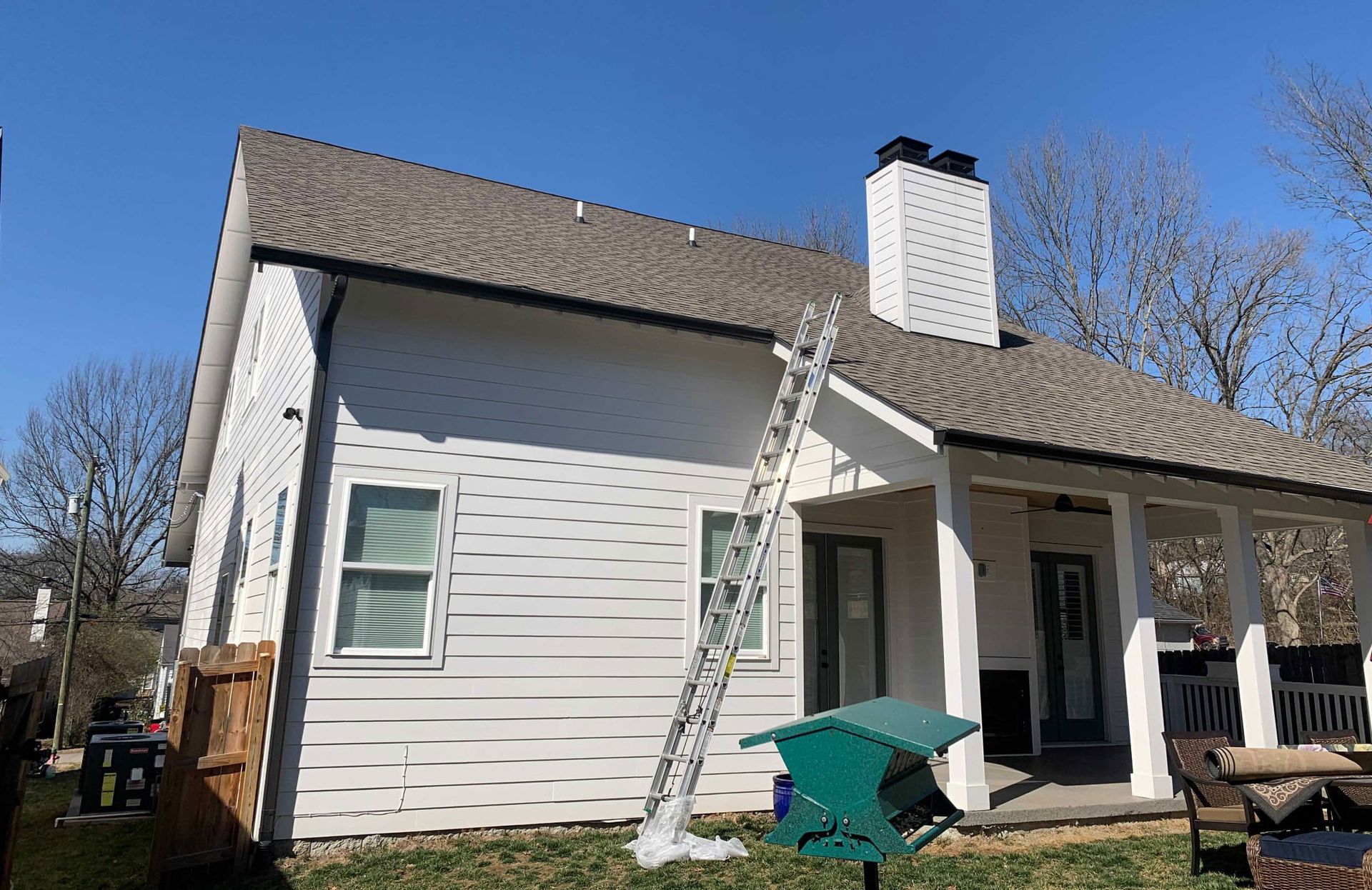 A white house with a bird feeder in front of it is being painted.