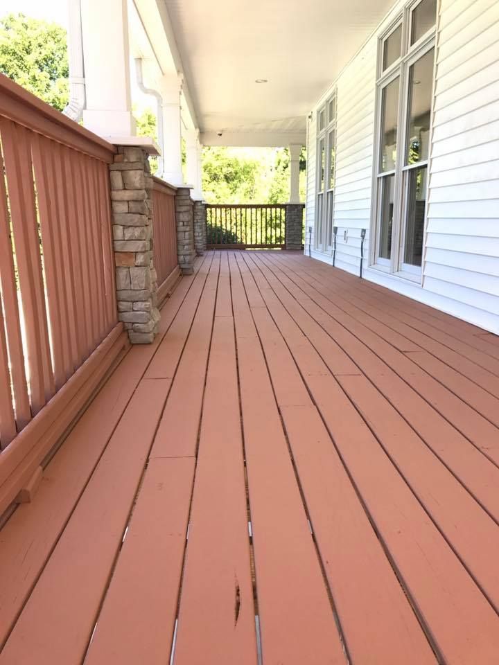 A large porch with a white house in the background