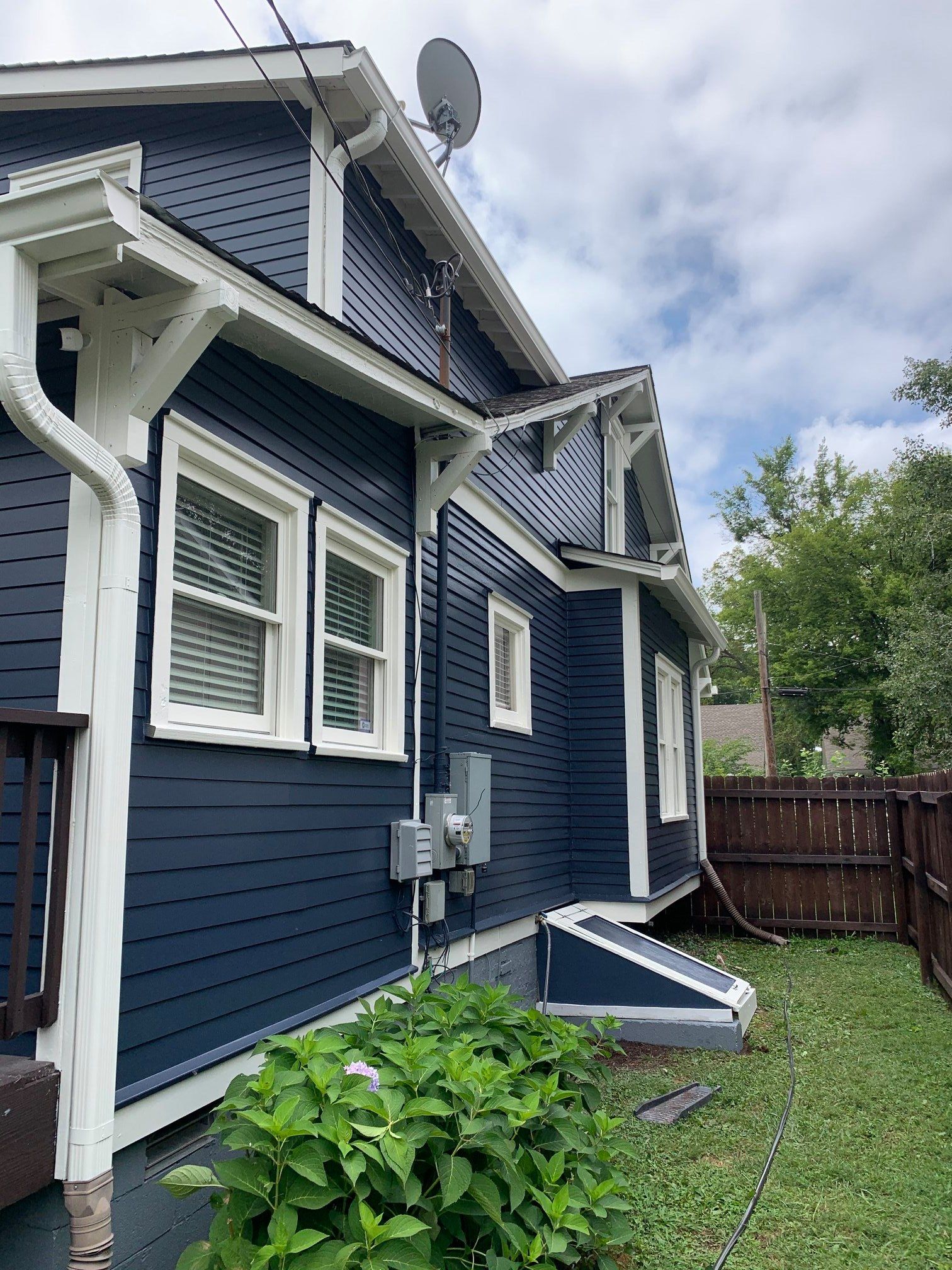 A blue house with white trim and a satellite dish on the roof.