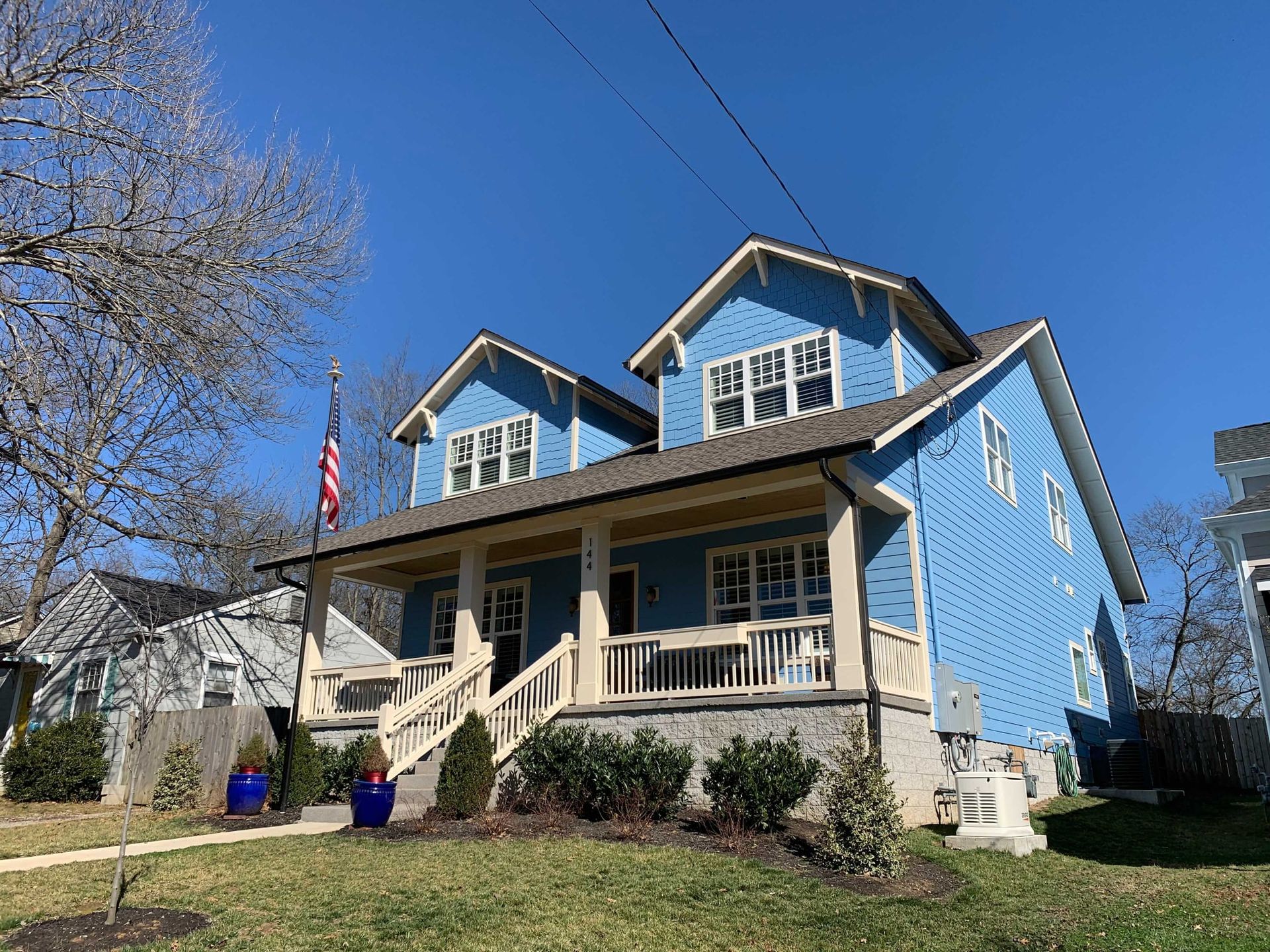 A blue house with a porch and stairs on a sunny day.