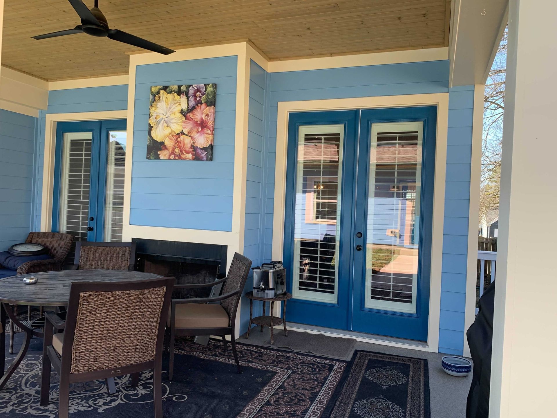 A blue porch with a table and chairs and a ceiling fan