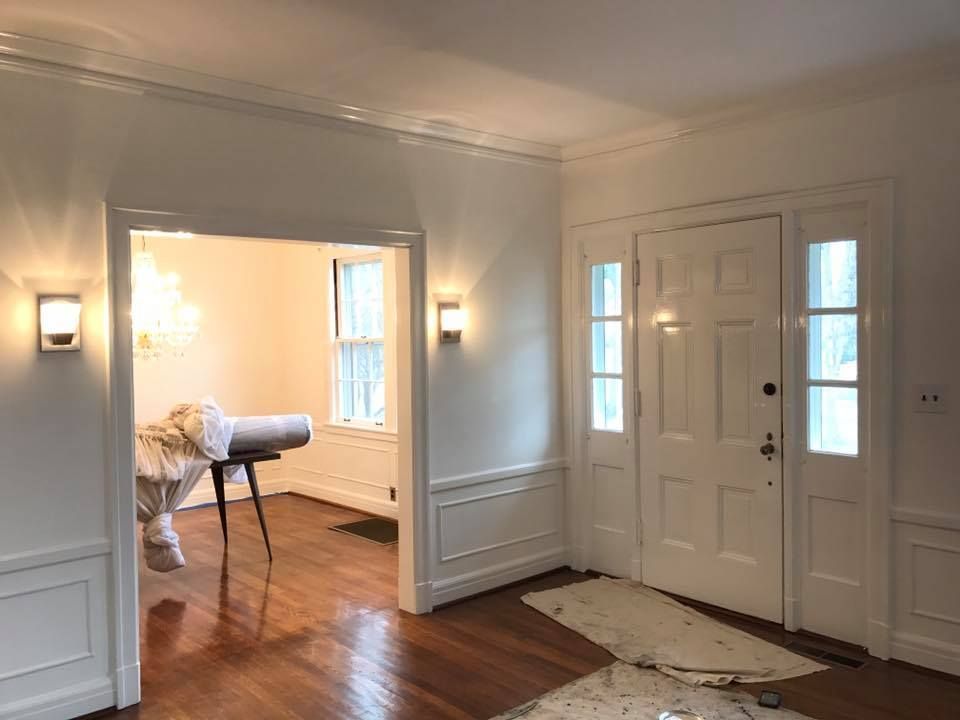 A living room with hardwood floors and white walls and a door.