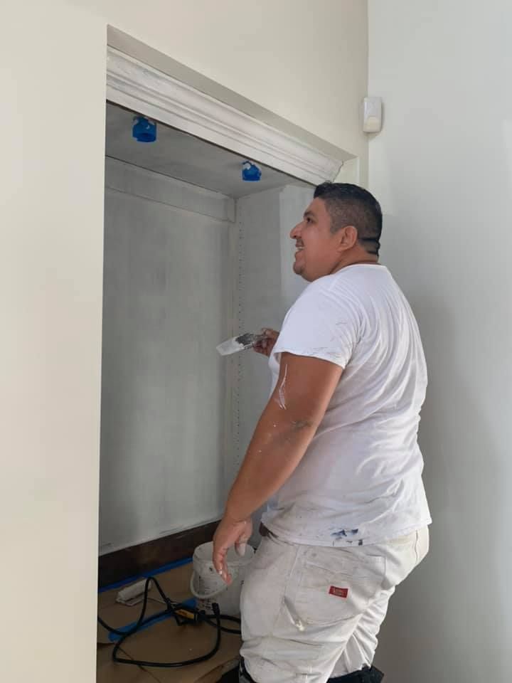 A man in a white shirt is painting a wall.