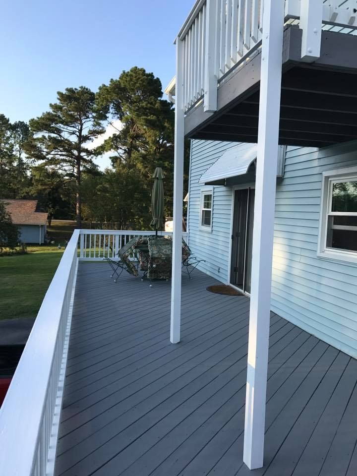 A blue house with a gray deck and white railing