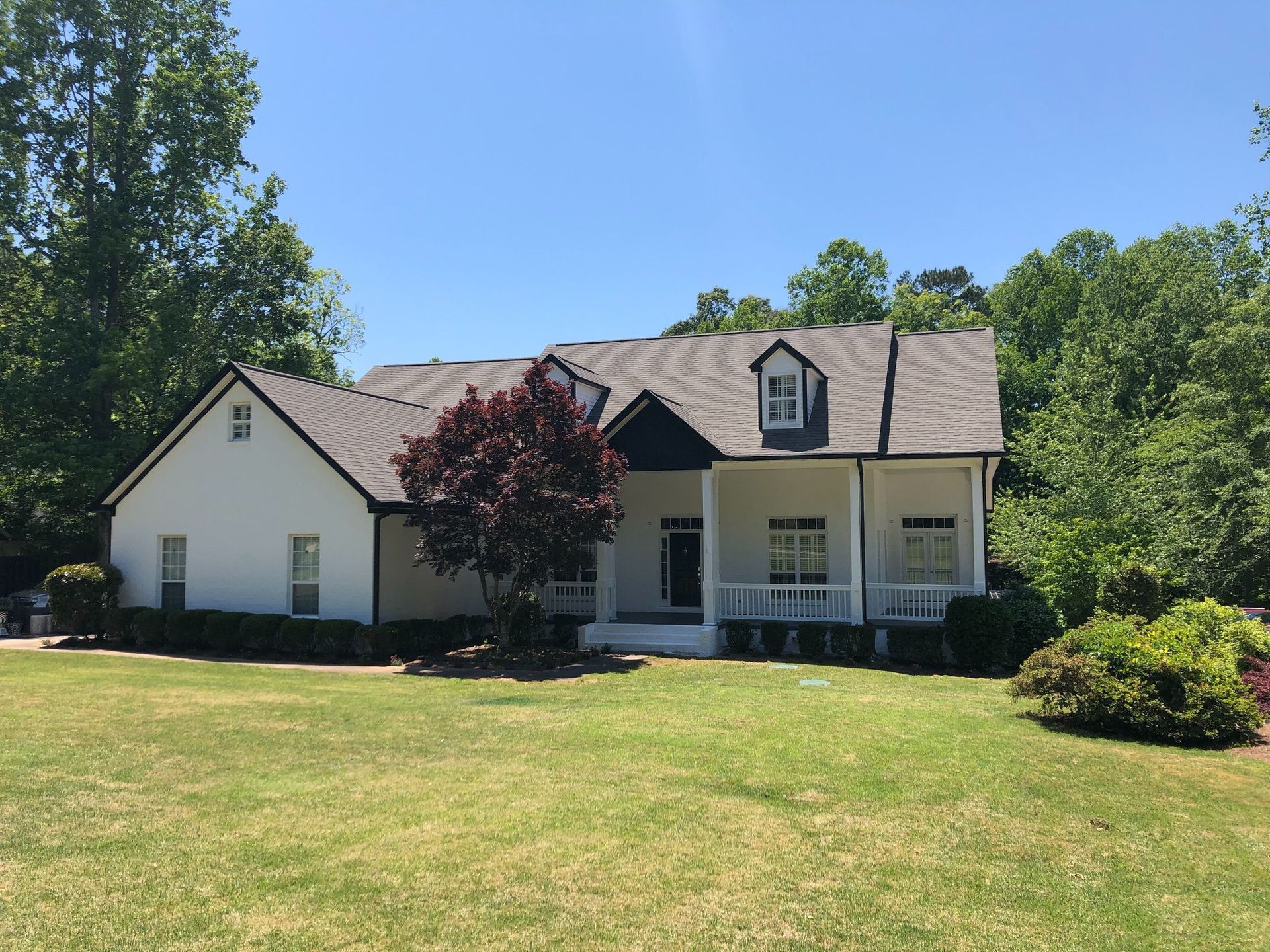 A white house with a porch and a tree in front of it