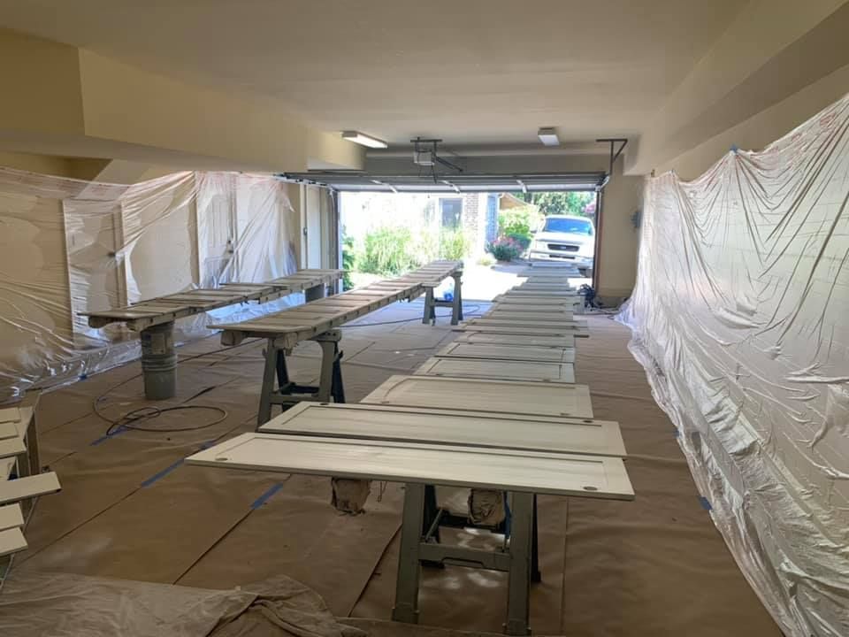 A row of tables are sitting in a garage covered in plastic.